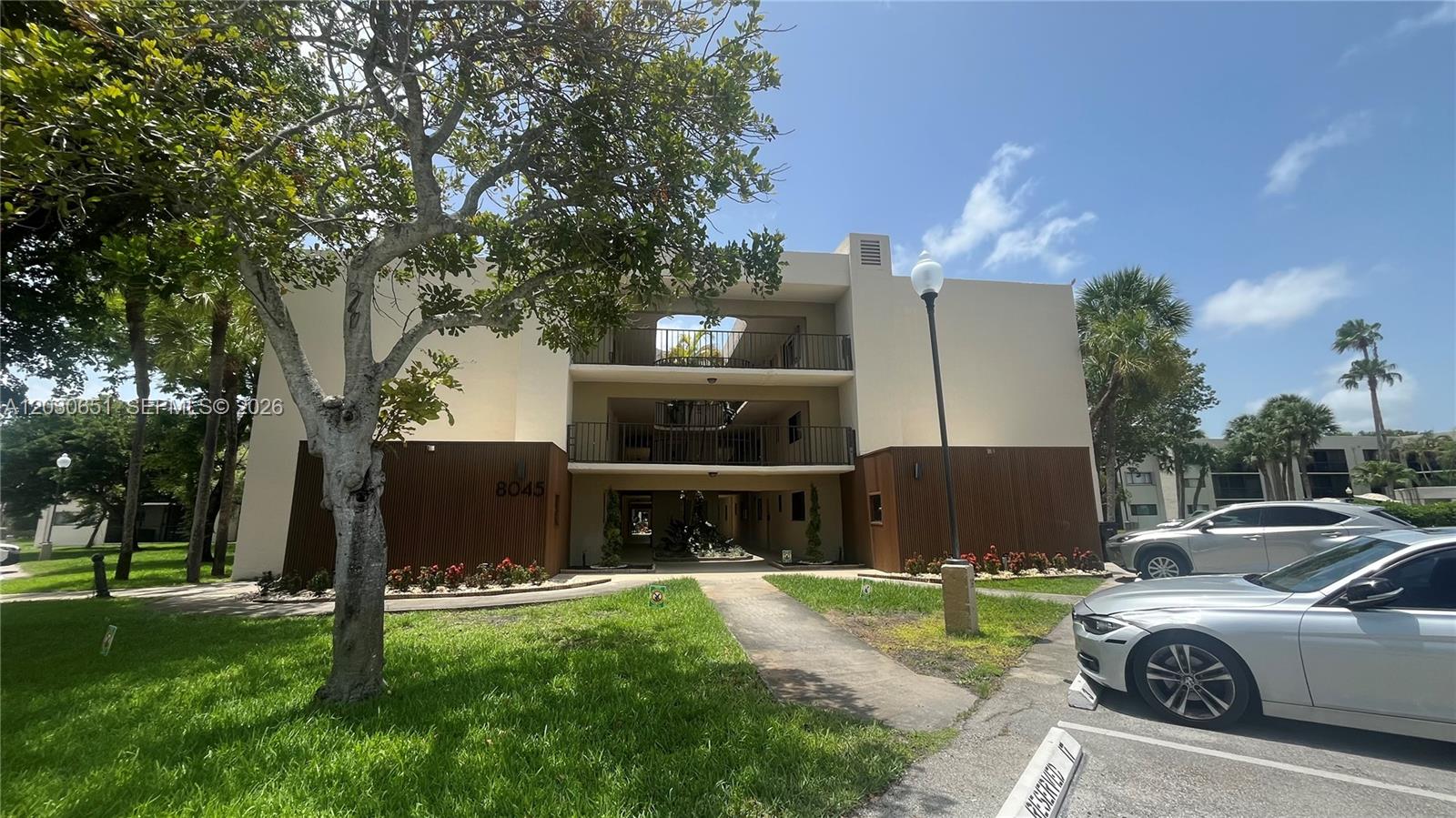 A three-story apartment building features a central open-air walkway and a parking lot — 8045 SW 107th Ave # 217, Miami FL 33173, MIAMI, FL