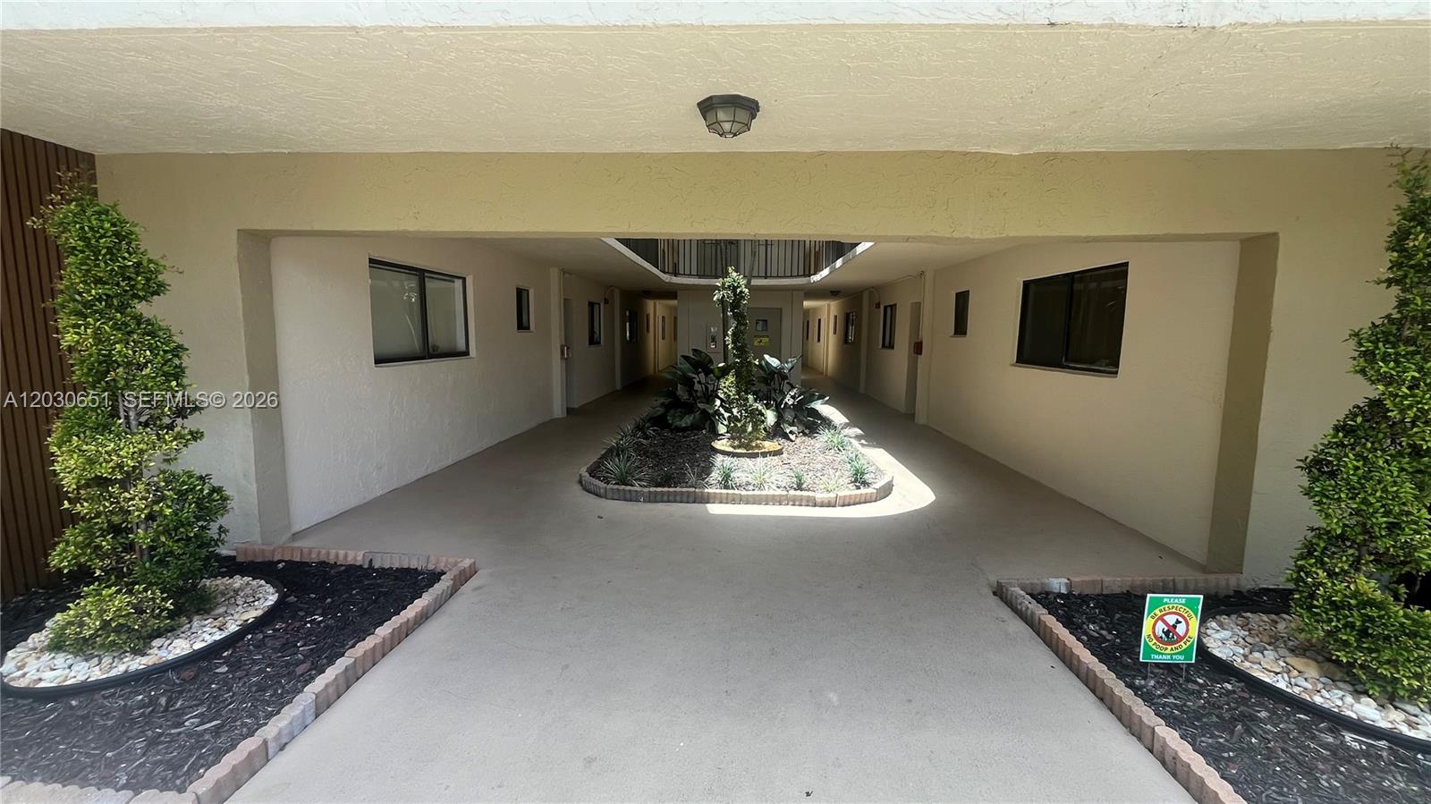 An outdoor breezeway features a central garden bed surrounded by a concrete walkway — 8045 SW 107th Ave # 217, Miami FL 33173, MIAMI, FL