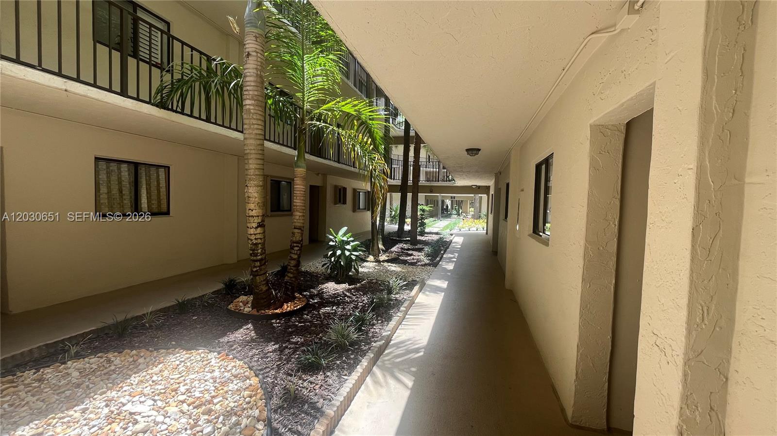An outdoor walkway between apartment buildings features palm trees, landscaping, and a concrete path — 8045 SW 107th Ave # 217, Miami FL 33173, MIAMI, FL