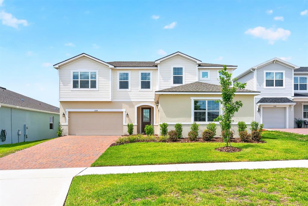 A two-story suburban house features a tan stucco and cream siding exterior with a brick driveway — 3520 BANANA SHRUB BOULEVARD, CLERMONT, FL