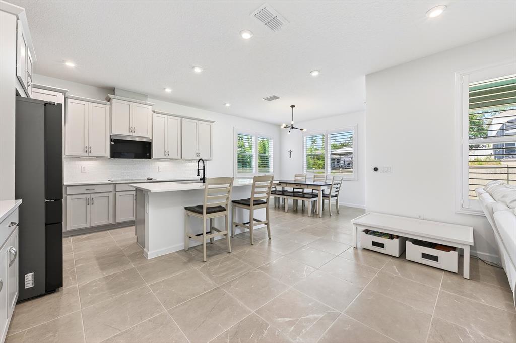 A modern kitchen and dining area with light gray cabinets, white countertops, and tile flooring — 3520 BANANA SHRUB BOULEVARD, CLERMONT, FL