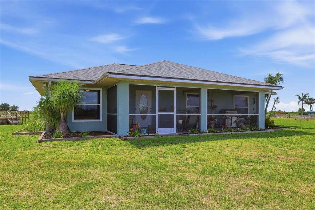 A concrete driveway leads through a gated wooden fence into a large, grassy rural property — 13105 MJ ROAD, MYAKKA CITY, FL