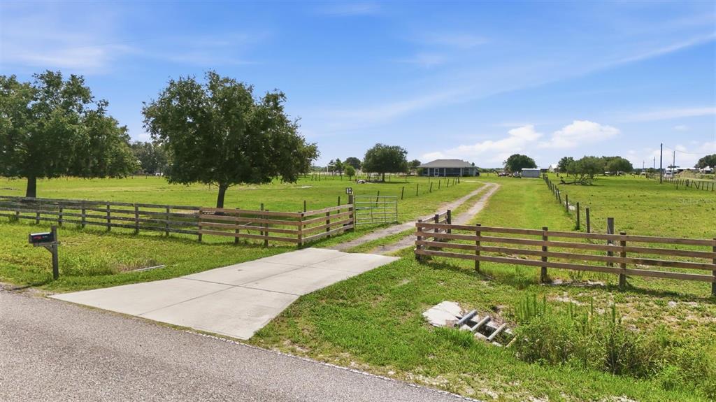 A single-story house with a screened-in porch and a light green exterior sits on grass — 13105 MJ ROAD, MYAKKA CITY, FL