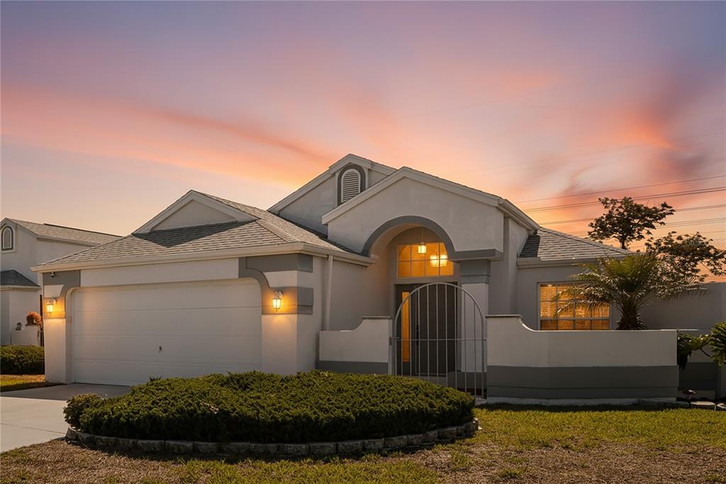 A single-story house with a two-car garage, arched entryway, and a landscaped front yard — 1018 CASTILLE DRIVE, SPRING HILL, FL