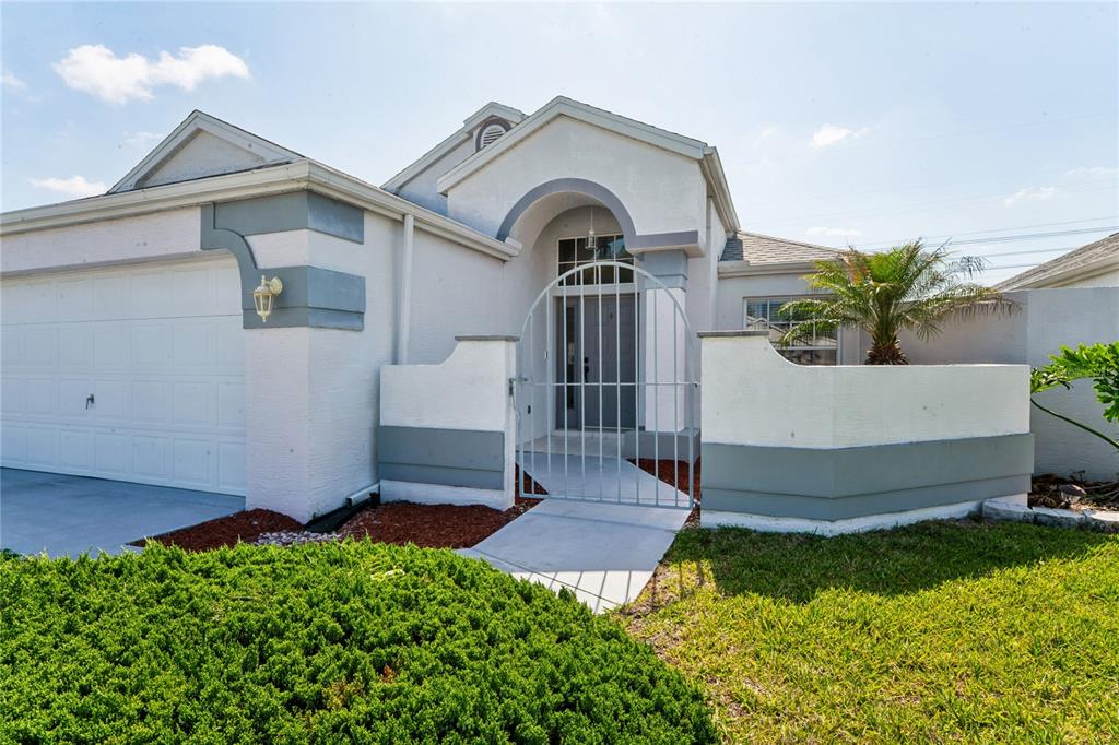 A single-story house with a white stucco exterior, a garage, and a gated front courtyard — 1018 CASTILLE DRIVE, SPRING HILL, FL