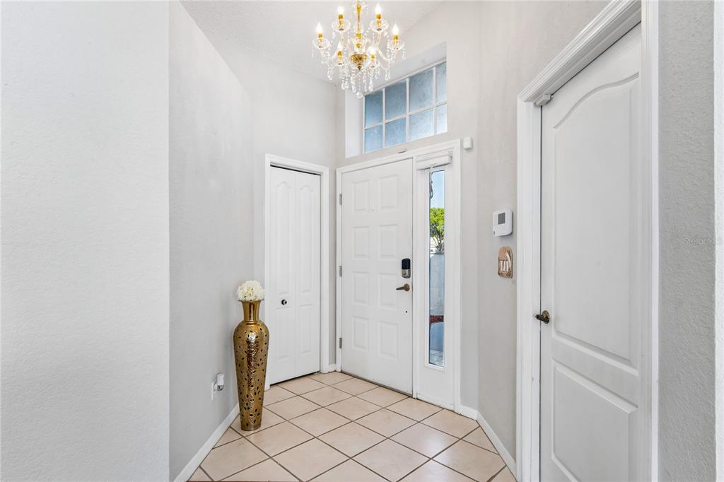 An entryway features a tiled floor, a chandelier, and white doors under a high ceiling — 1018 CASTILLE DRIVE, SPRING HILL, FL