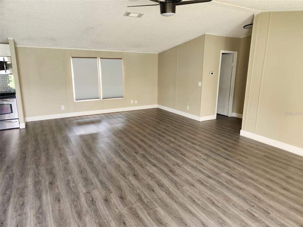 A spacious living area features light-colored walls, wood-look flooring, and a ceiling fan — 9653 4TH AVENUE, ORLANDO, FL