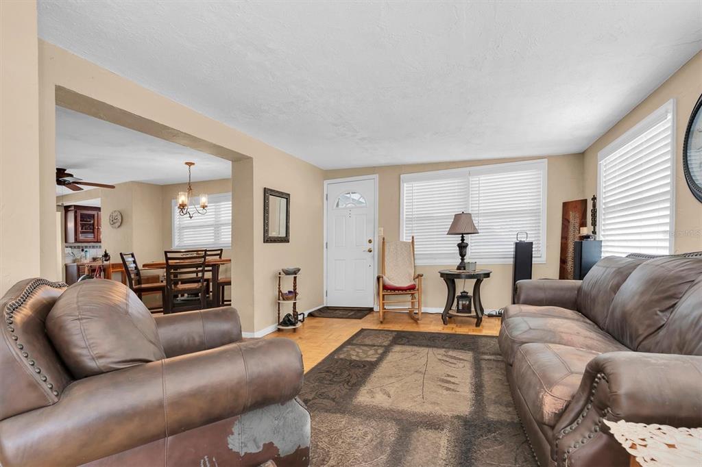 A living room with brown leather furniture, a patterned area rug, and an adjacent dining area — 3227 48TH AVENUE N, ST PETERSBURG, FL