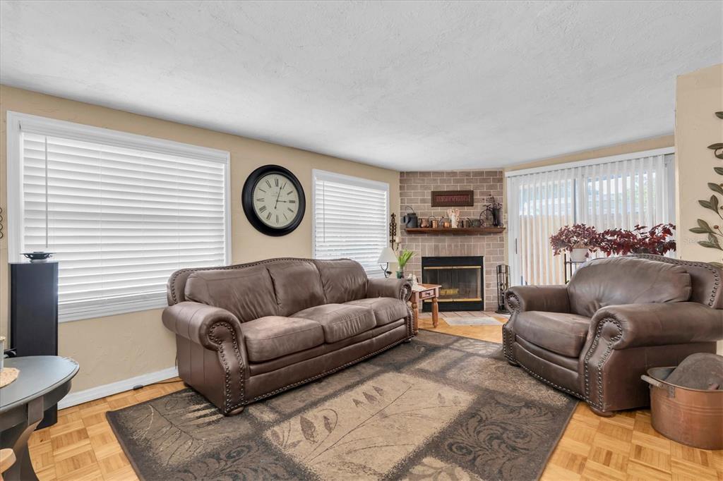 A living room features a brown leather sofa and armchair on a patterned area rug — 3227 48TH AVENUE N, ST PETERSBURG, FL