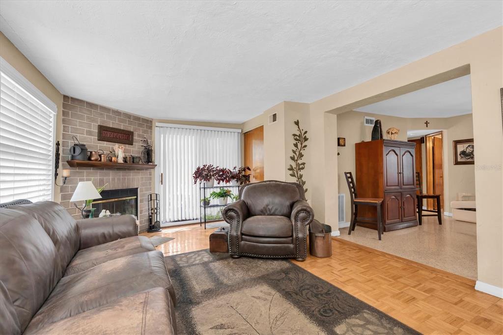 A living room features a brick fireplace, leather furniture, hardwood flooring, and an adjacent dining area — 3227 48TH AVENUE N, ST PETERSBURG, FL