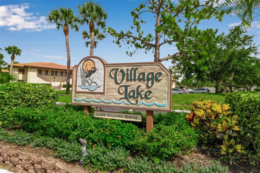 A sign for Village Lake stands in front of a building and landscaping — 5224 LAKE VILLAGE DRIVE UNIT 67, SARASOTA, FL