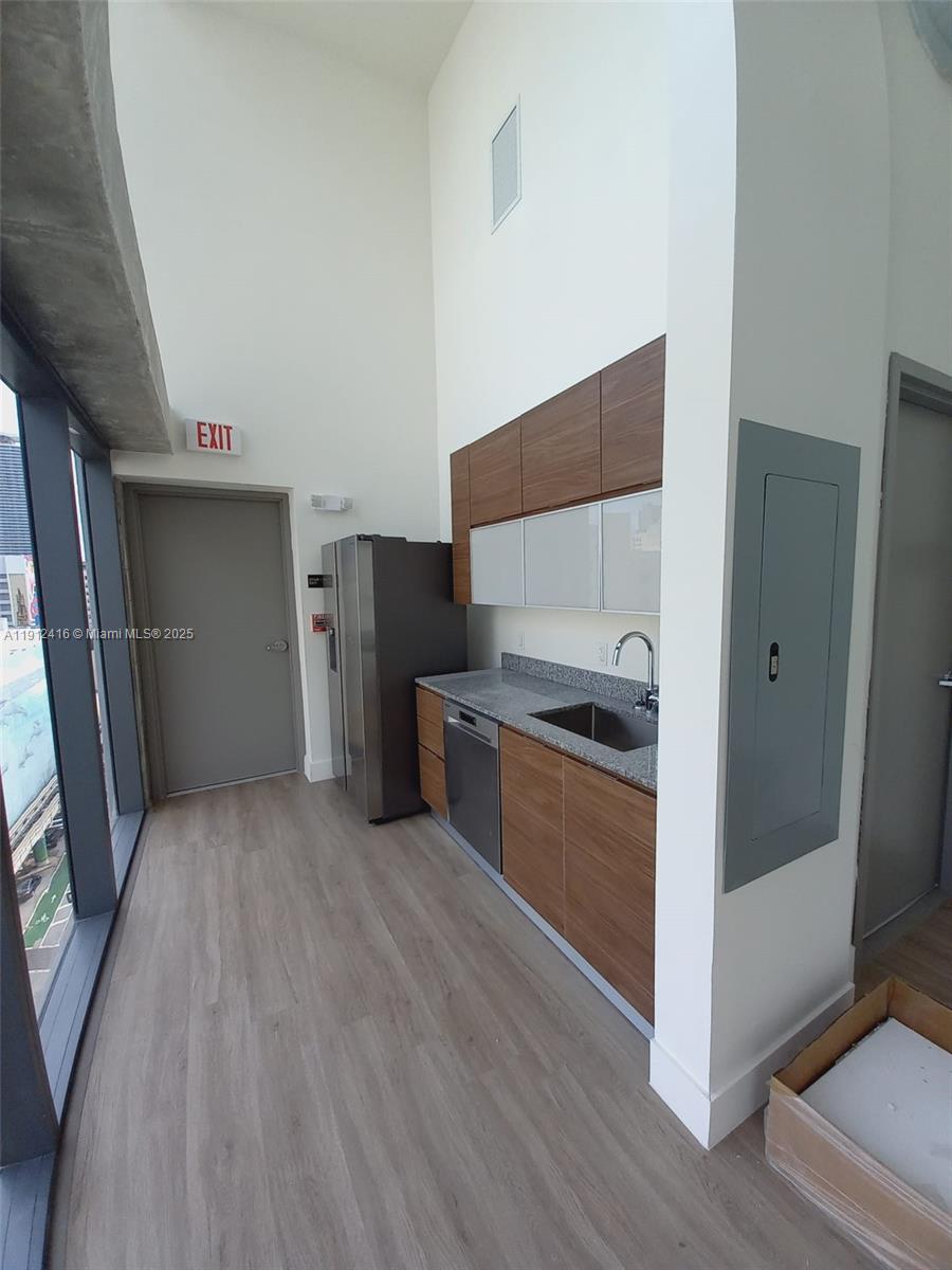 A modern kitchenette features wood-tone cabinetry, stainless steel appliances, and a gray countertop — 30 SW 1st St # 601, Miami FL 33130, MIAMI, FL