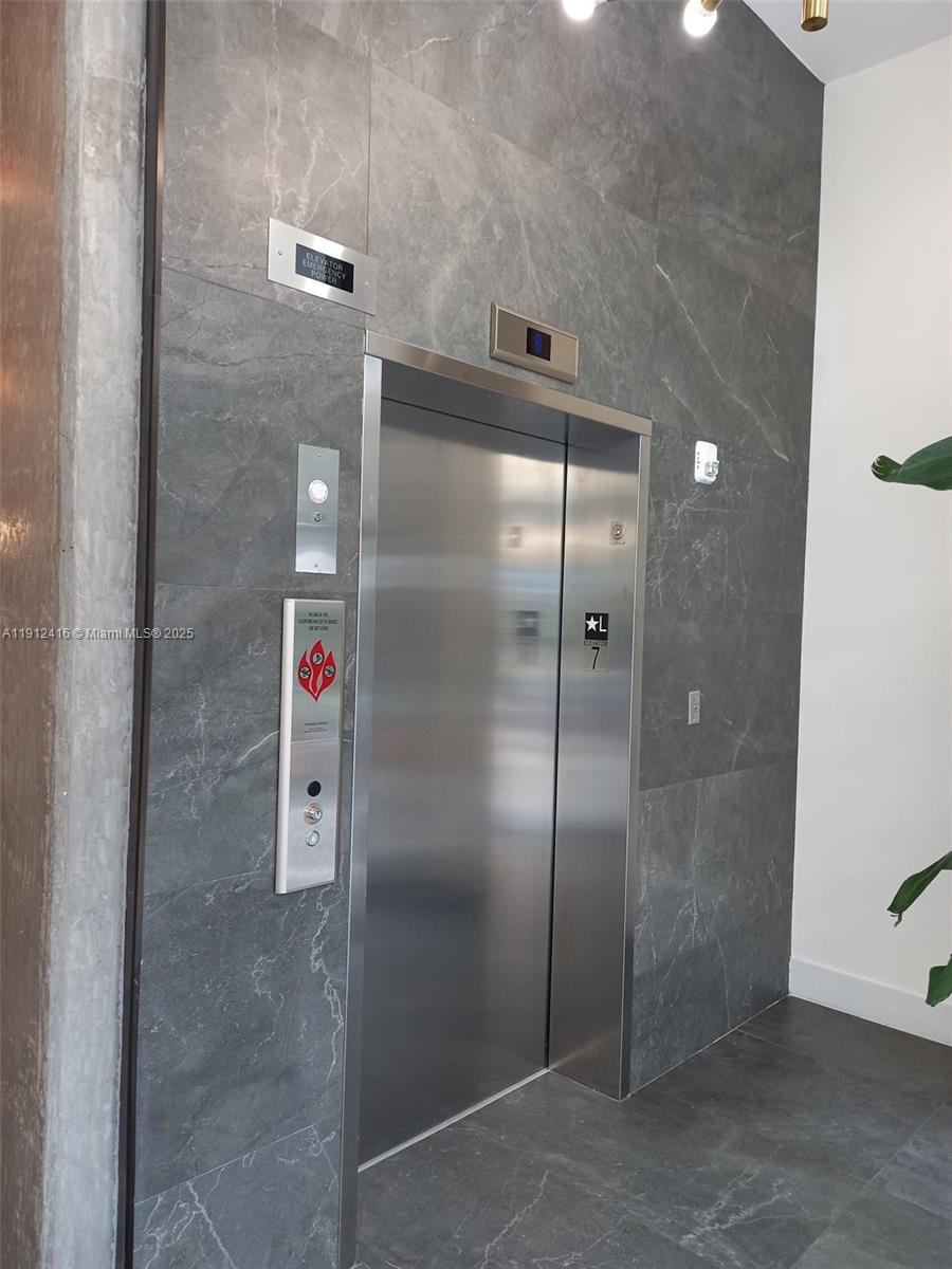 A stainless steel elevator door is set into a wall with dark gray marble tiles — 30 SW 1st St # 601, Miami FL 33130, MIAMI, FL