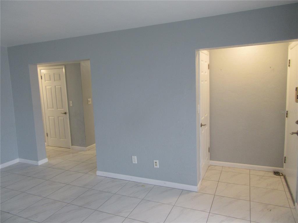 A room with light blue walls, white tile flooring, and two doorways leading to other areas — 110 60TH AVENUE UNIT 1, ST PETE BEACH, FL