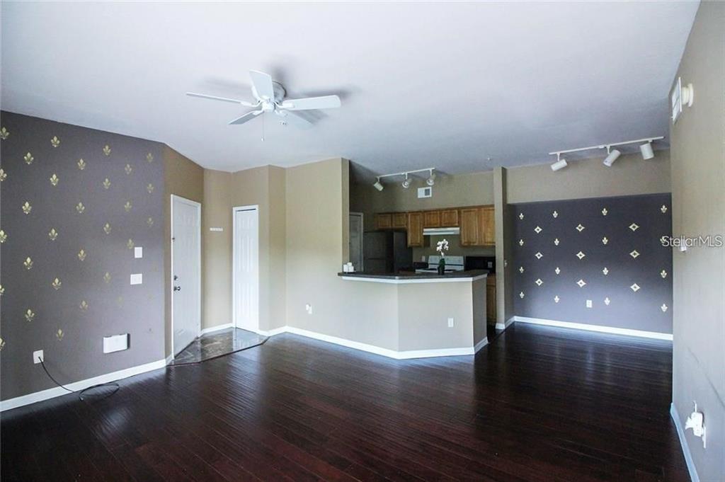 An open-concept living room and kitchen area with dark wood floors and accent walls — 6029 WESTGATE DRIVE UNIT 725, ORLANDO, FL