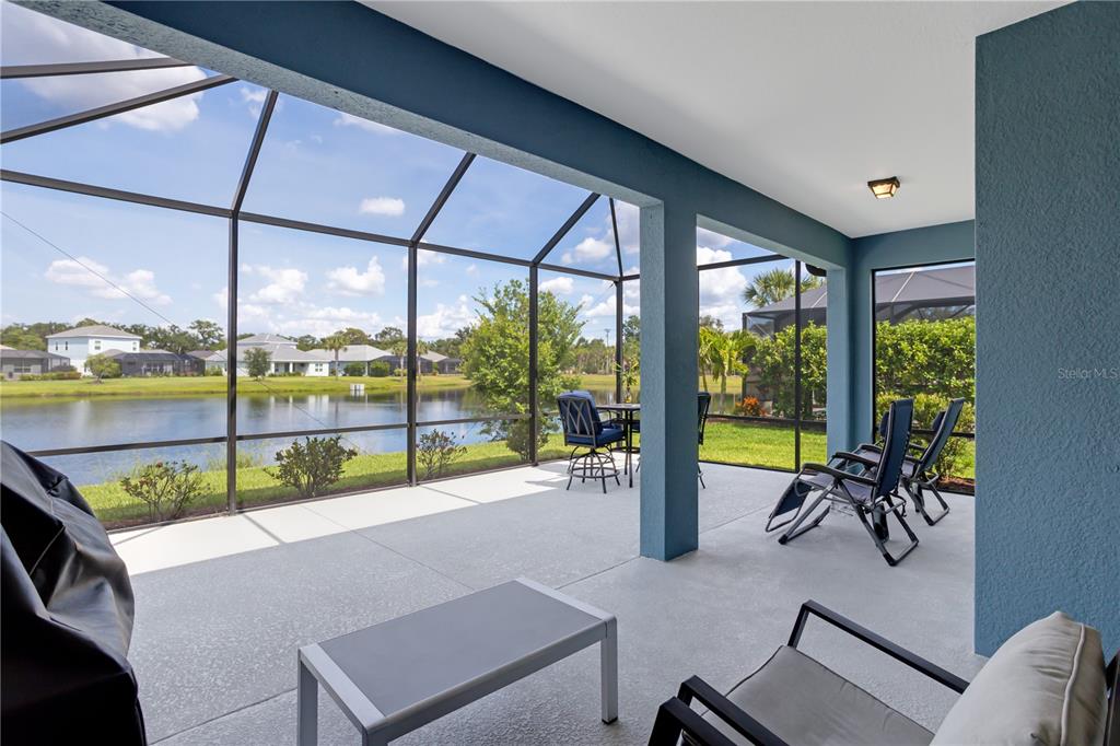 A screened-in patio with concrete flooring overlooks a lake and neighboring houses — 3410 BOX TURTLE TERRACE, PARRISH, FL