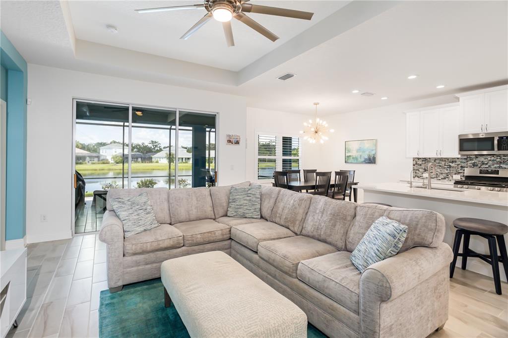 An open-concept living room and kitchen feature a sectional sofa, dining area, and lake view — 3410 BOX TURTLE TERRACE, PARRISH, FL