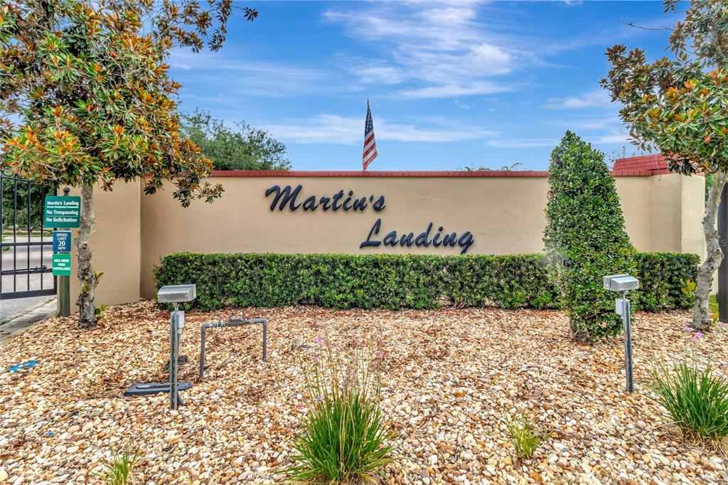 A beige wall with the text Martin's Landing stands behind a gravel bed and landscaping — 10838 PRIEBE ROAD, CLERMONT, FL