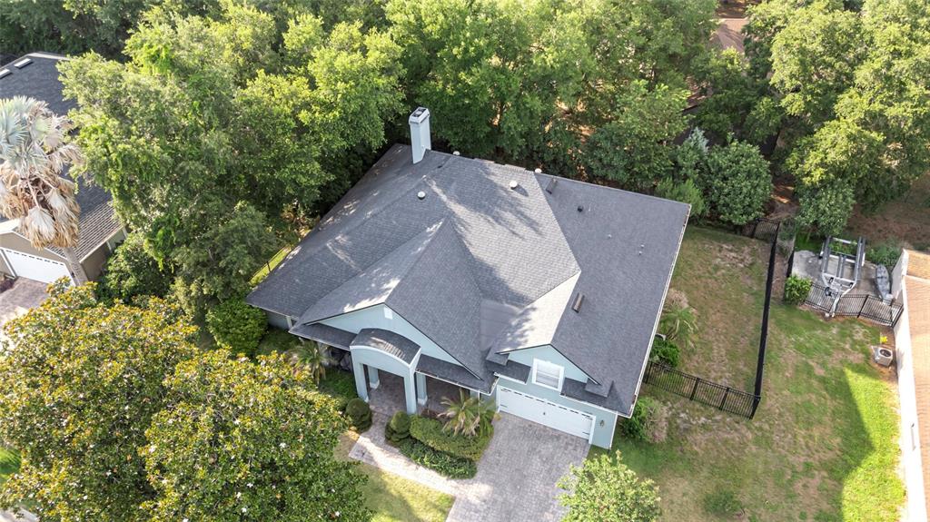 An aerial view shows a house with a gray shingled roof, driveway, and surrounding trees — 10838 PRIEBE ROAD, CLERMONT, FL