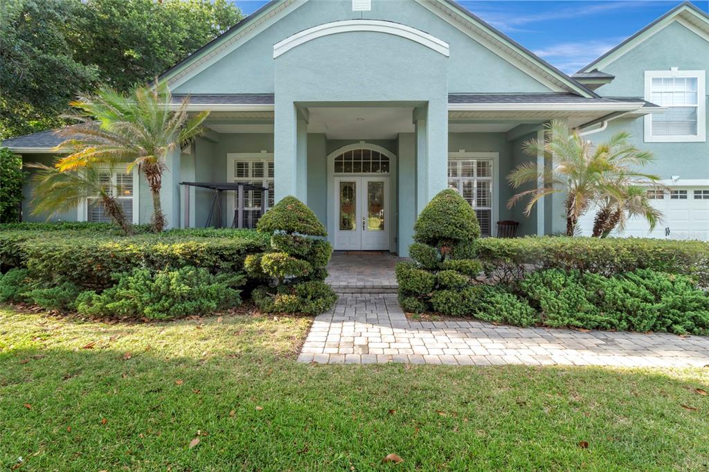 A light blue house with a paved walkway leading to a double-door front entrance — 10838 PRIEBE ROAD, CLERMONT, FL