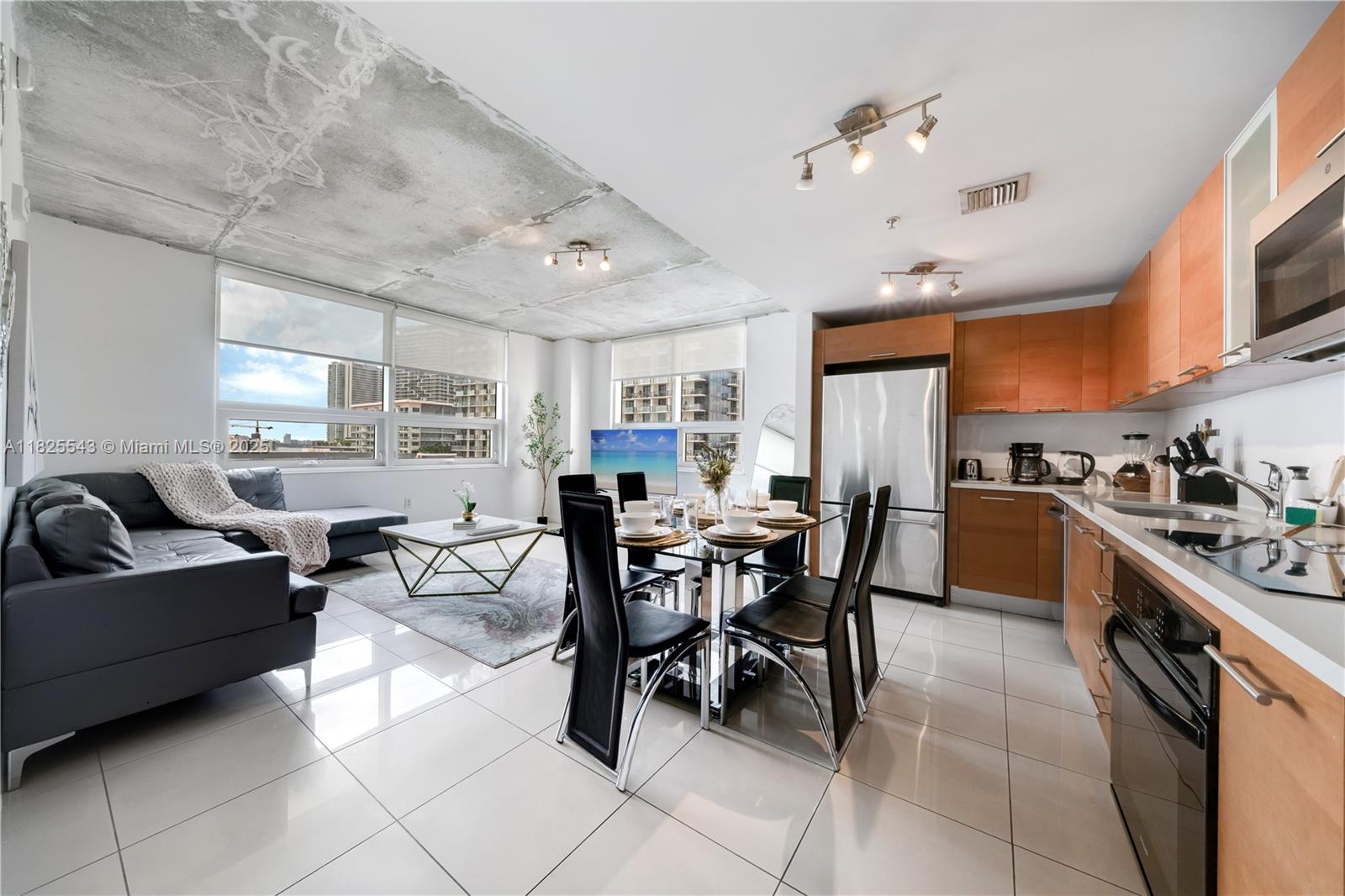 An open-concept living and dining area features a concrete ceiling, tile floors, and wood cabinetry — 3250 NE 1st Ave # 1016, Miami FL 33137, MIAMI, FL