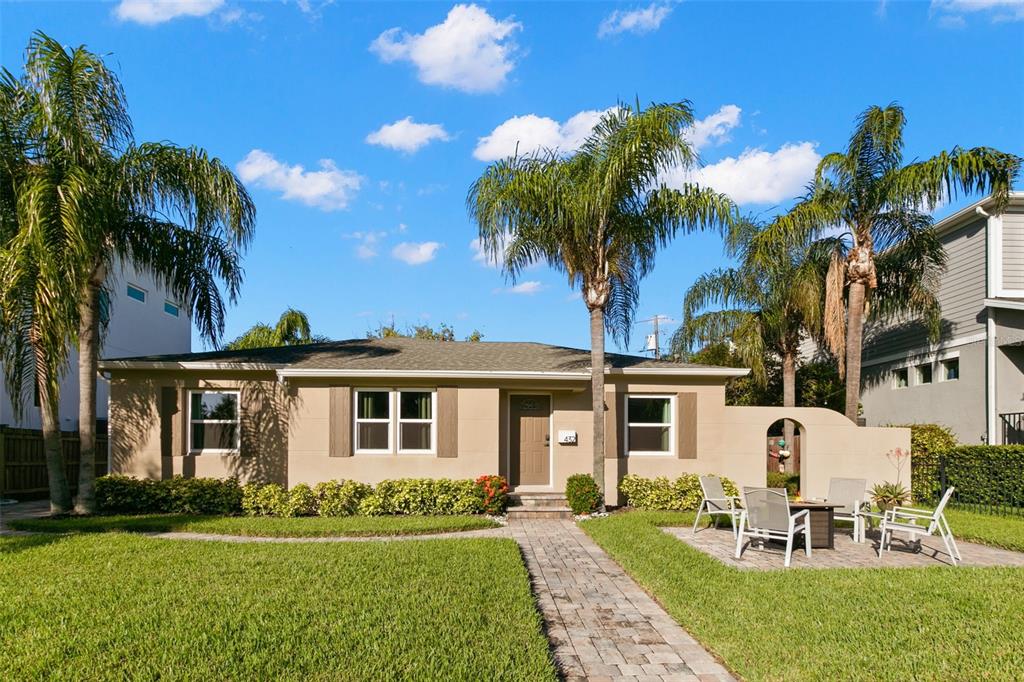 A single-story tan house with a paved walkway, palm trees, and a front patio area — 432 E DAVIS BOULEVARD, TAMPA, FL