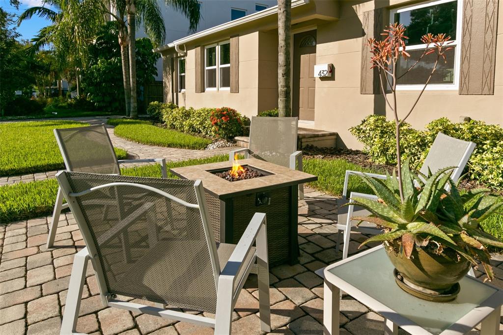 A patio with a fire pit and four chairs sits in front of a house exterior — 432 E DAVIS BOULEVARD, TAMPA, FL