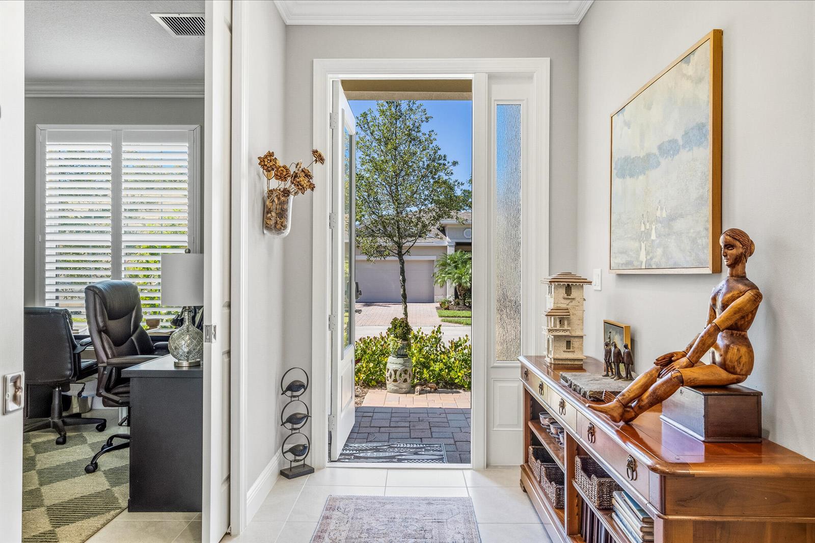 An entryway with a wooden console table, a decorative mannequin, and an open front door — 6012 Bella Rosa Lane, Vero Beach FL 32966, VERO BEACH, FL