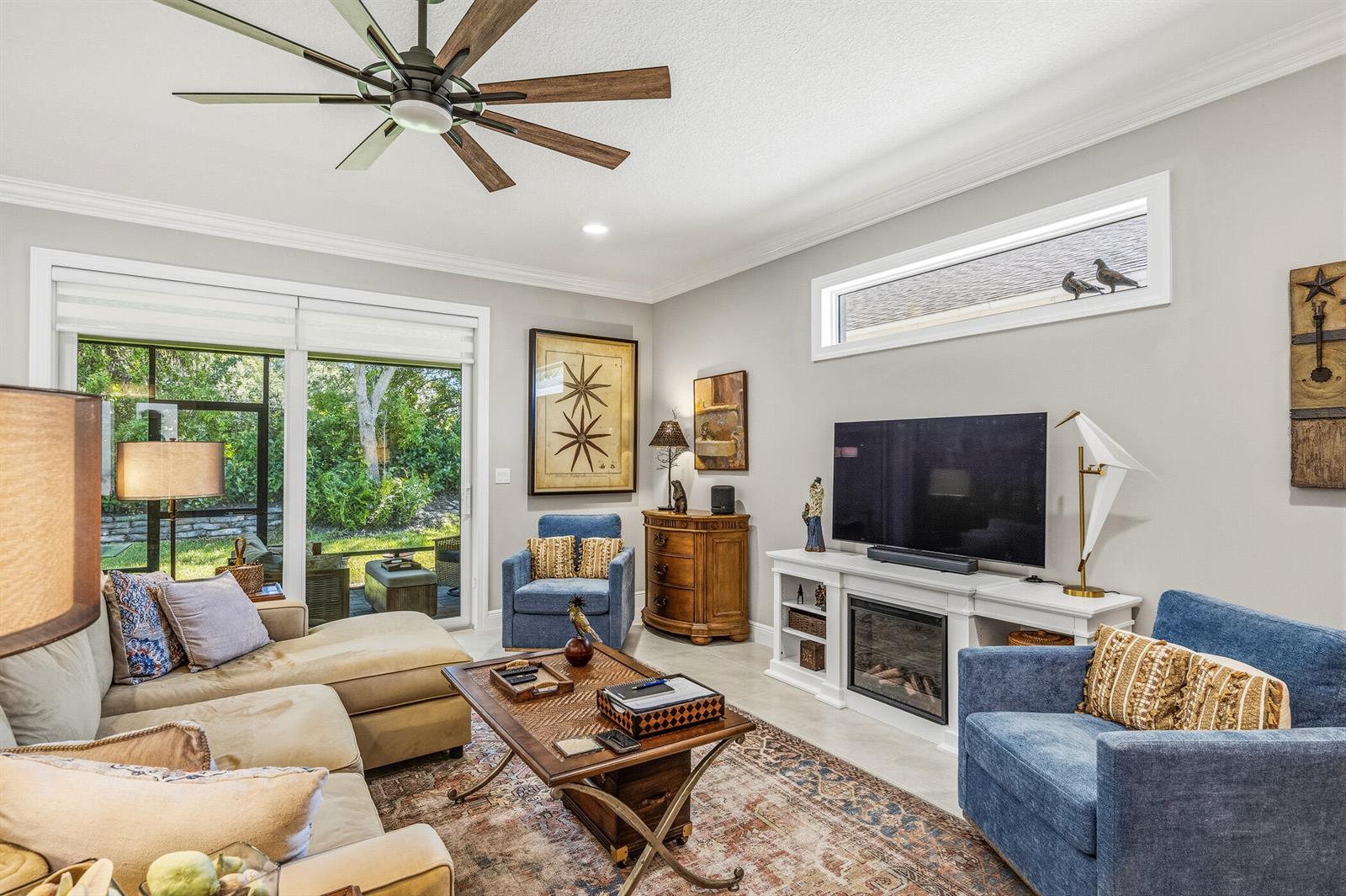 A living room features a beige sectional, blue armchairs, a fireplace, and a ceiling fan — 6012 Bella Rosa Lane, Vero Beach FL 32966, VERO BEACH, FL