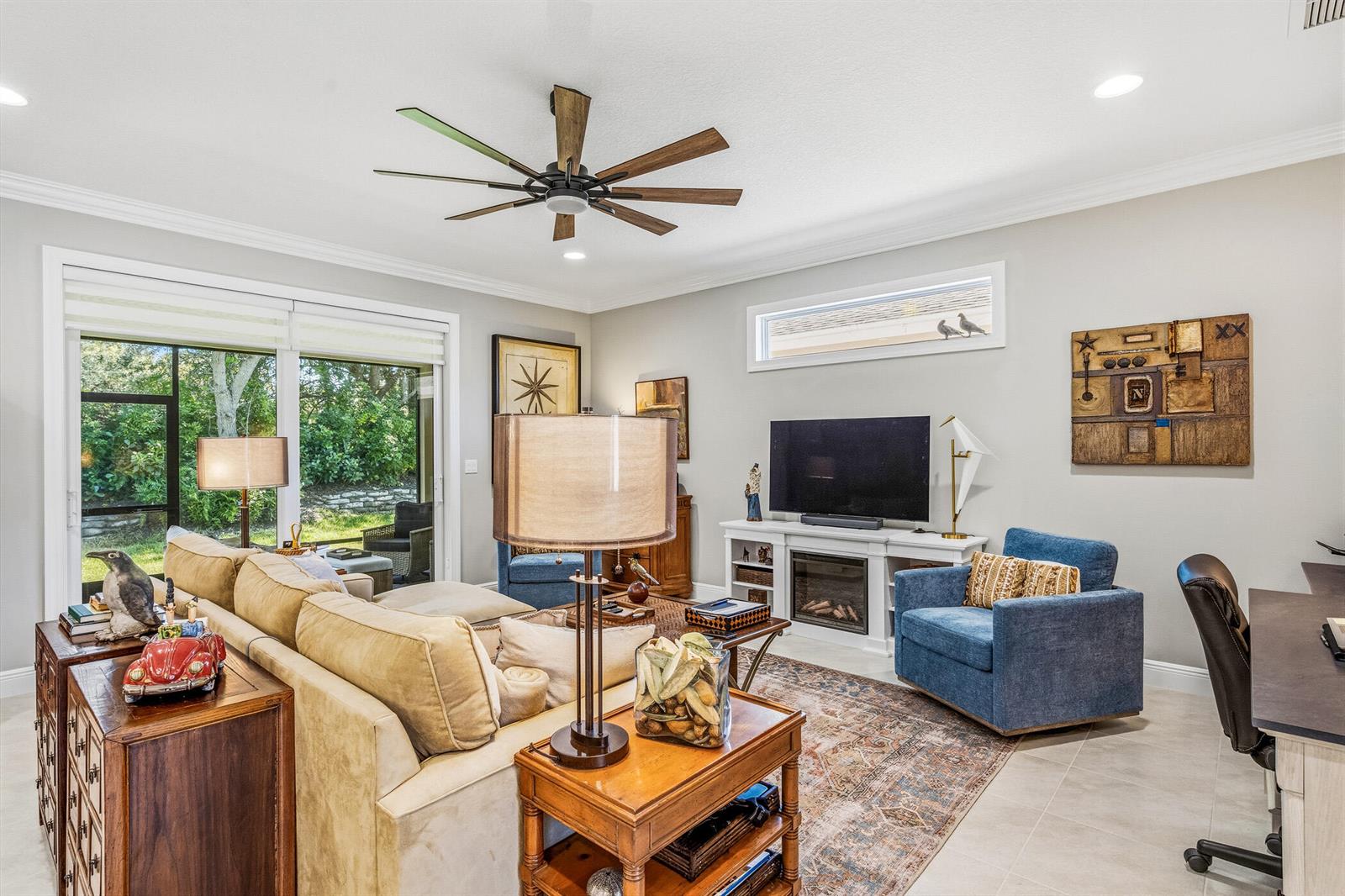 A living room features a beige sectional, blue armchairs, a television, and a ceiling fan — 6012 Bella Rosa Lane, Vero Beach FL 32966, VERO BEACH, FL