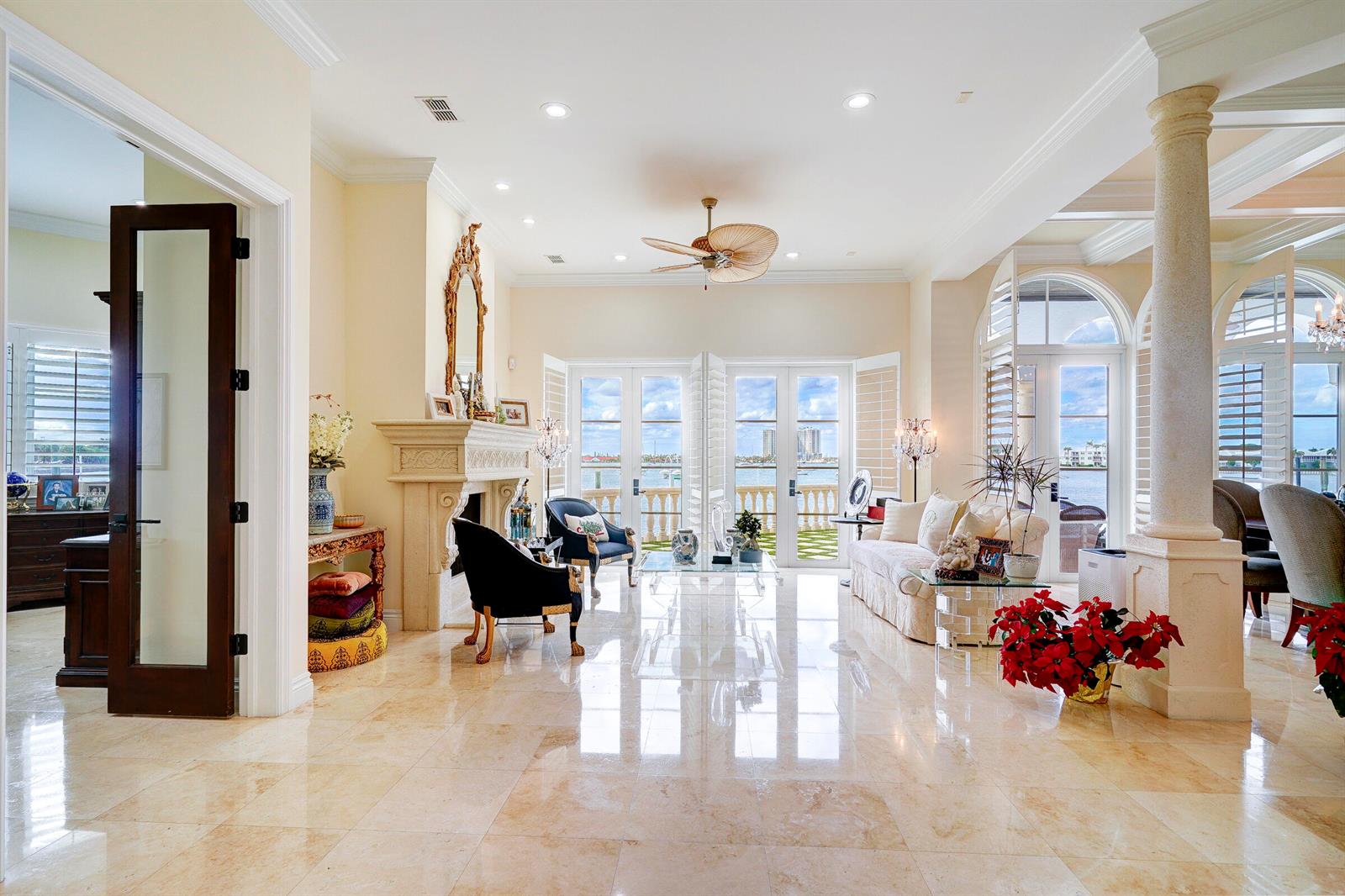 A bright living room with marble floors, a fireplace, and glass doors overlooking the water — 2775 Lake Drive, Singer Island FL 33404, SINGER ISLAND, FL