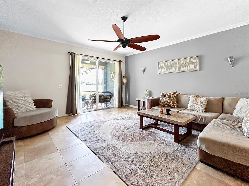 A living room features a sectional sofa, a stone coffee table, and a ceiling fan — 18141 NASSAU POINT DRIVE, TAMPA, FL