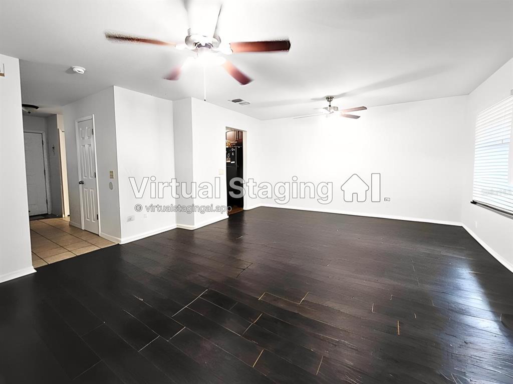 An empty living room features dark hardwood floors, white walls, and two ceiling fans — 11807 MINTWOOD COURT, ORLANDO, FL
