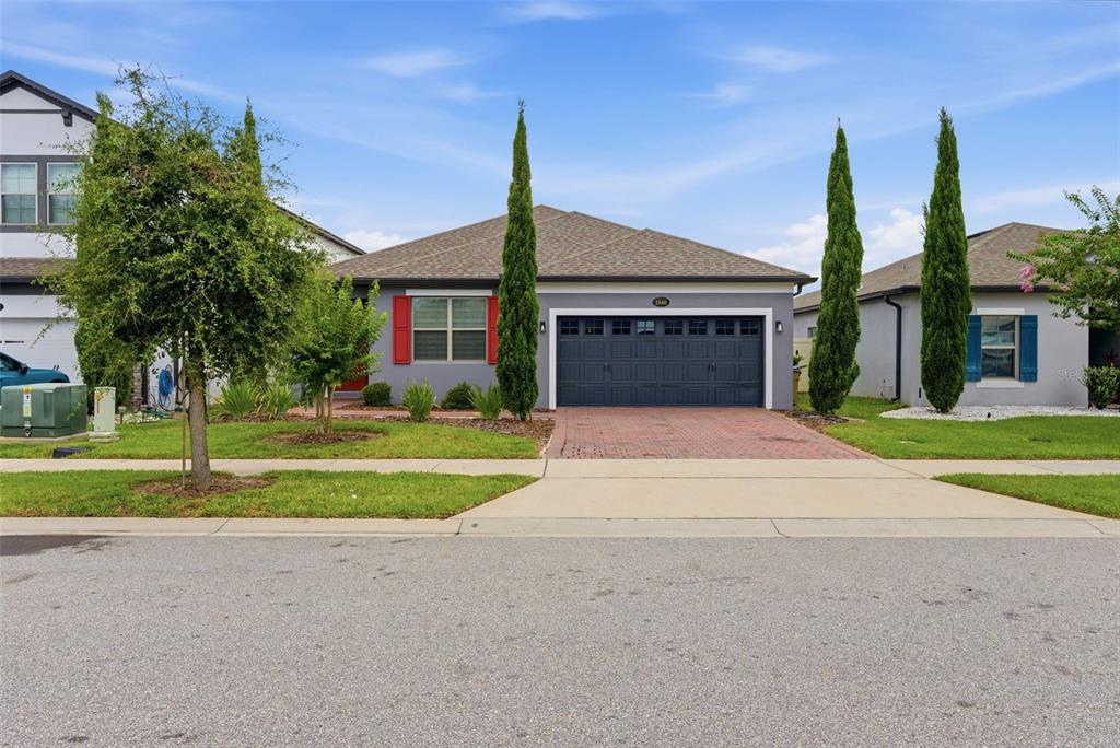A single-story house with a gray exterior, red shutters, and a two-car garage — 1840 NAPOLI DRIVE, ST CLOUD, FL