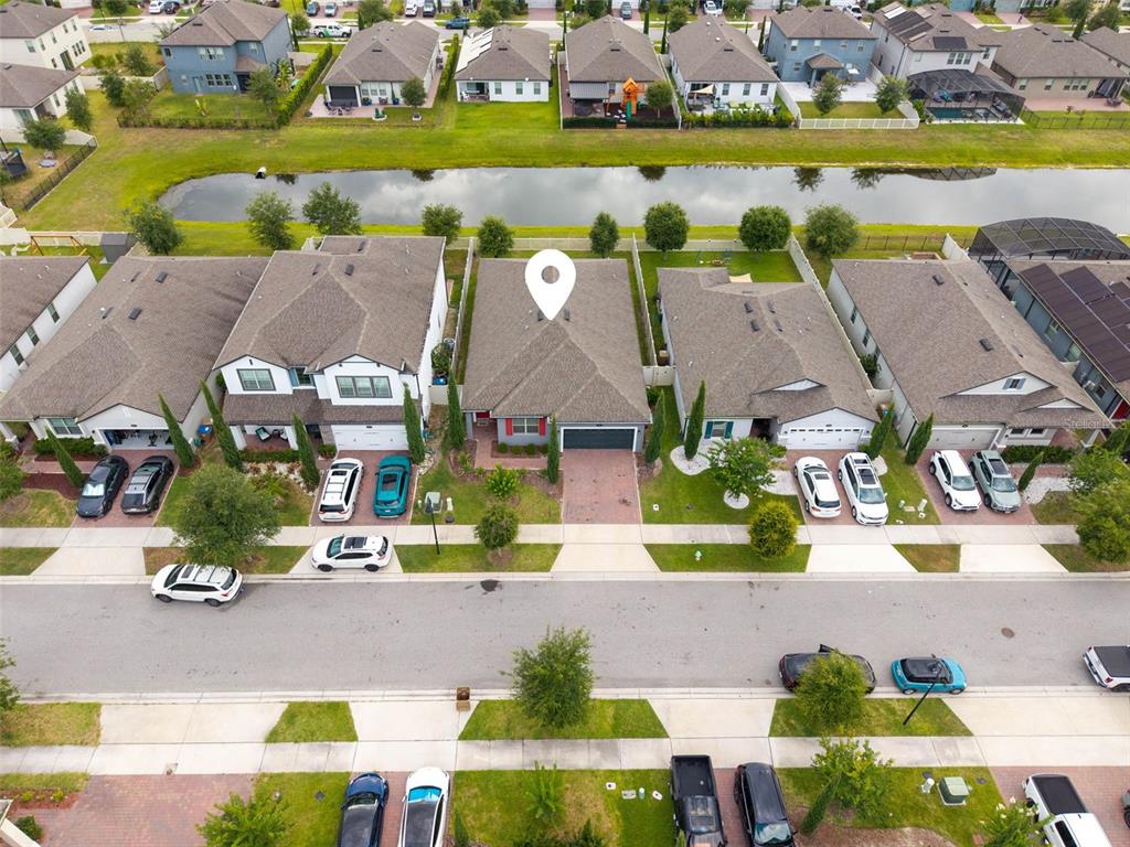 An aerial view shows a suburban neighborhood with houses, a canal, and parked cars — 1840 NAPOLI DRIVE, ST CLOUD, FL
