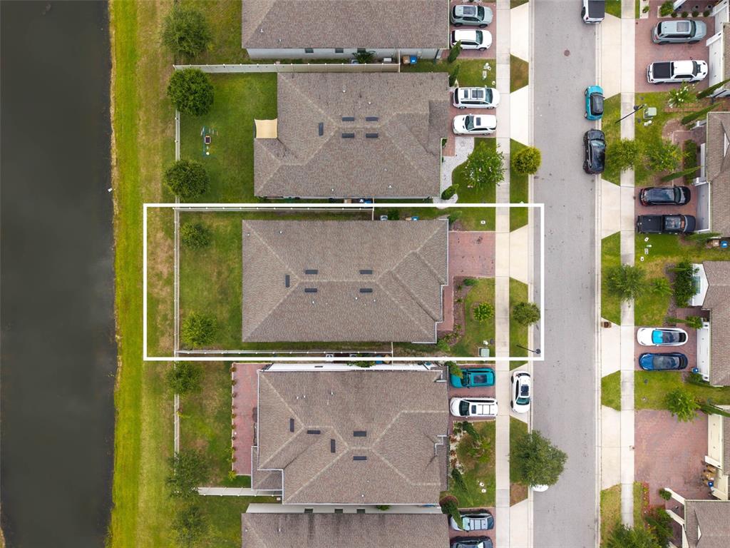 An aerial view shows a residential house with a fenced backyard bordering a canal — 1840 NAPOLI DRIVE, ST CLOUD, FL
