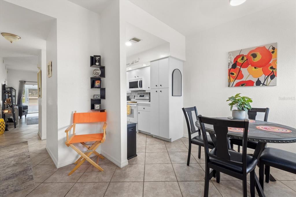 A dining area with a round table and chairs leads into a white kitchen — 5800 SABAL TRACE DRIVE UNIT 103, NORTH PORT, FL