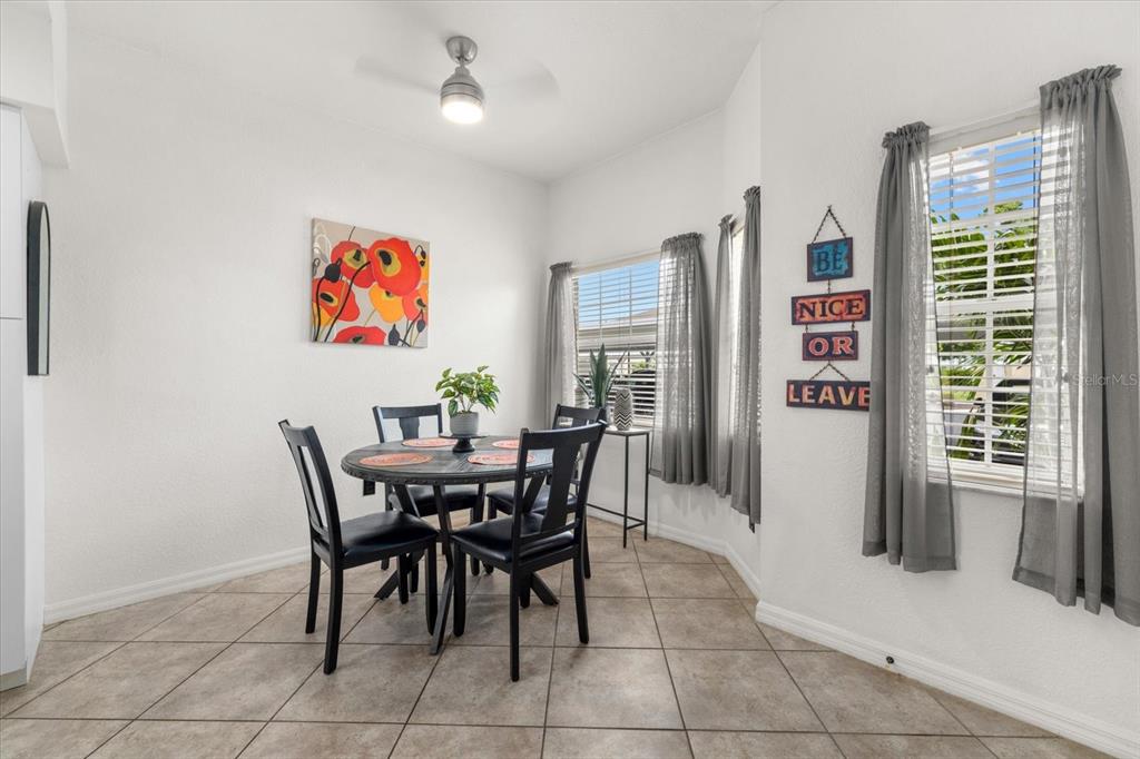 A dining area features a round table, four chairs, tile flooring, and two windows — 5800 SABAL TRACE DRIVE UNIT 103, NORTH PORT, FL