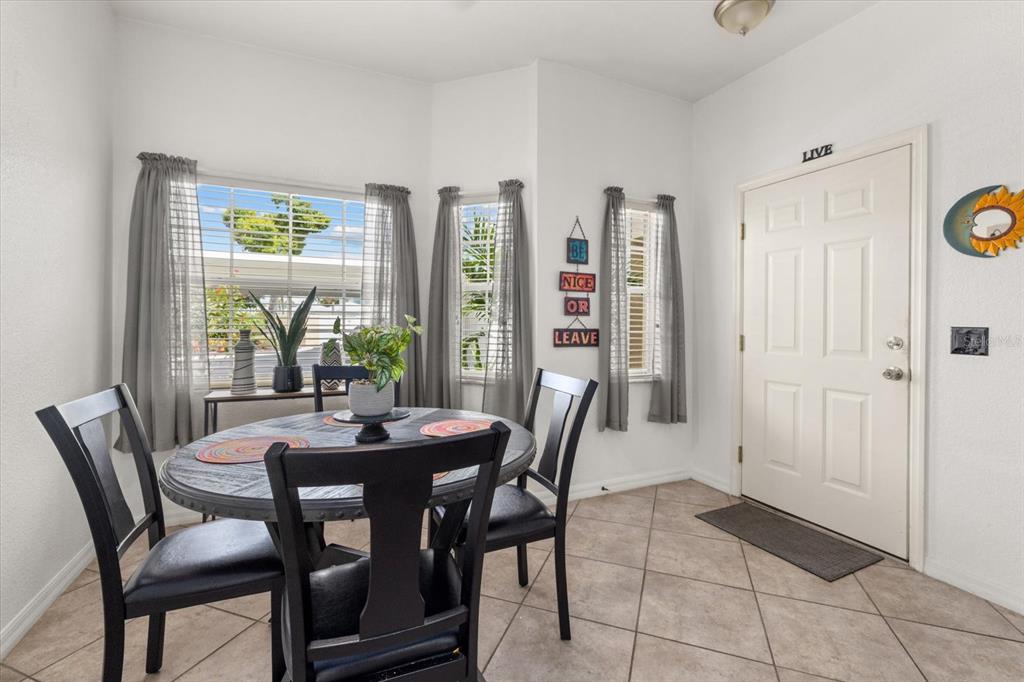 A dining area features a round table, four chairs, tile flooring, and a front door — 5800 SABAL TRACE DRIVE UNIT 103, NORTH PORT, FL