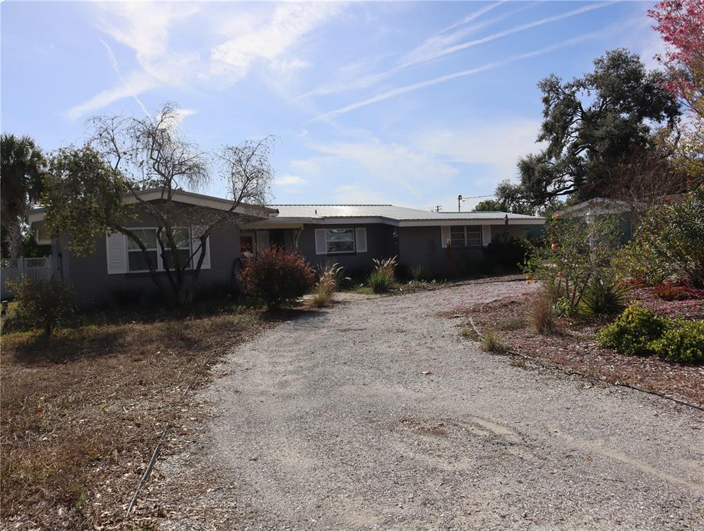 A single-story gray house with a gravel driveway and a metal roof — 940 OLEANDER DRIVE SE, WINTER HAVEN, FL