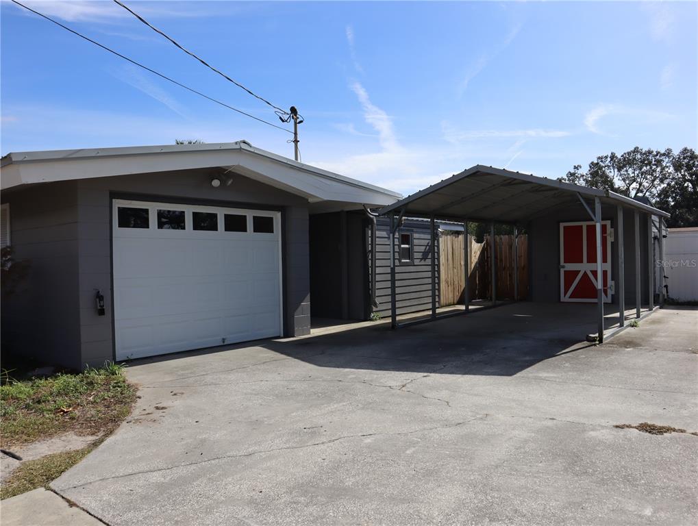 A gray house features a white garage door and an attached metal carport — 940 OLEANDER DRIVE SE, WINTER HAVEN, FL