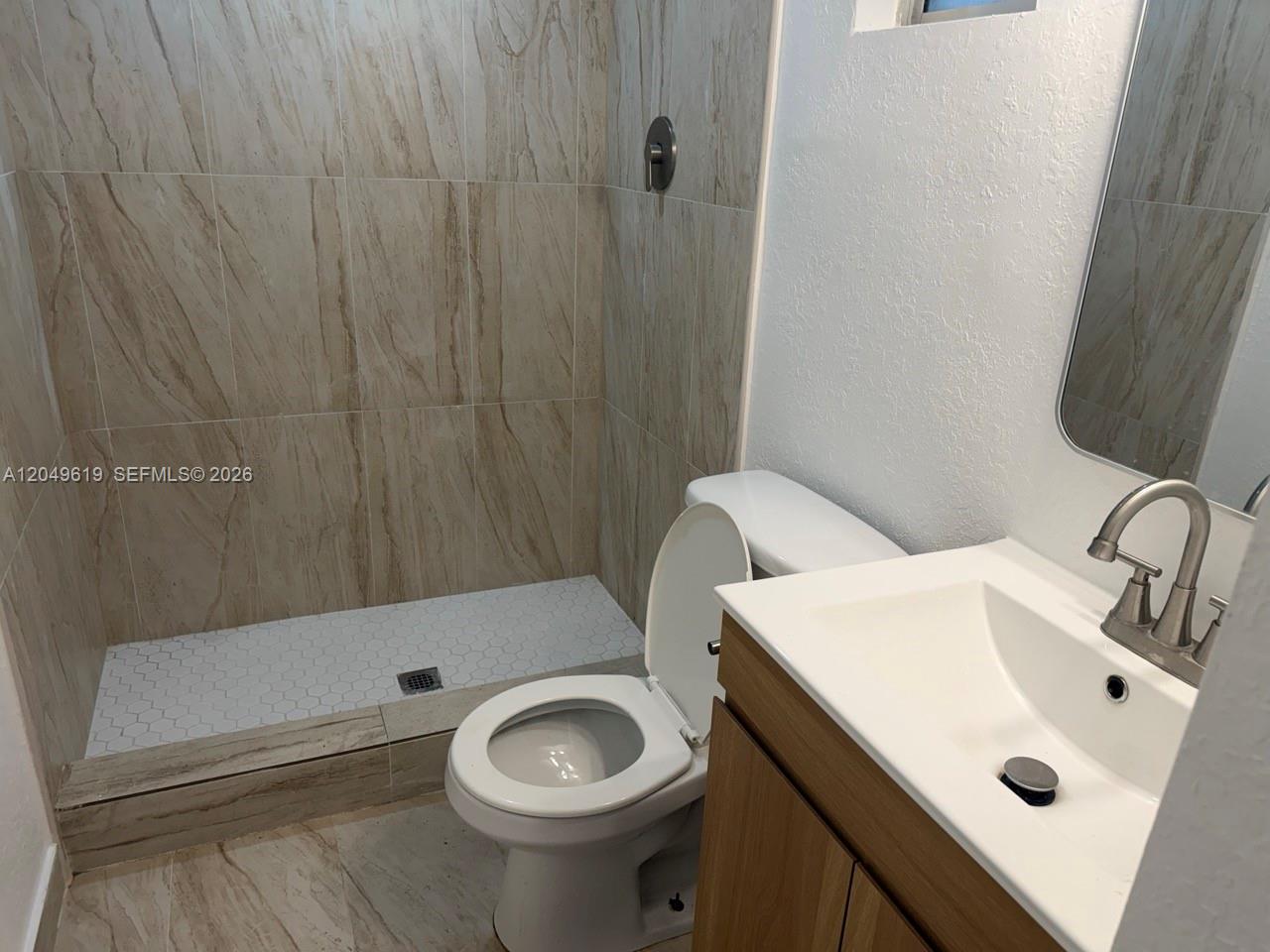 A bathroom features a walk-in shower with tiled walls, a toilet, and a vanity sink — 219 SW 21st Ave # 5, Miami FL 33135, MIAMI, FL
