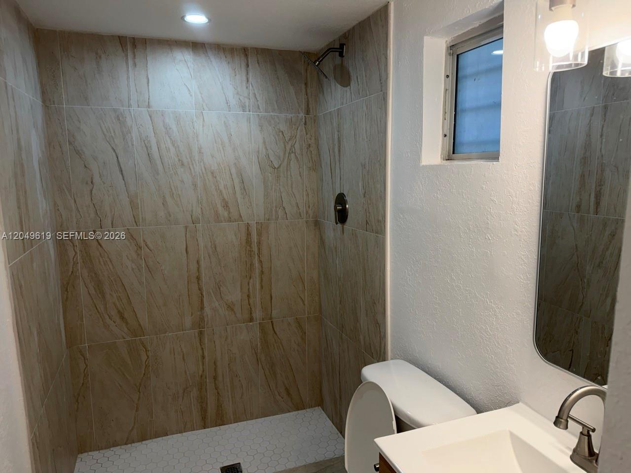 A bathroom features a walk-in shower with tan marble-look tiles and a white vanity — 219 SW 21st Ave # 5, Miami FL 33135, MIAMI, FL