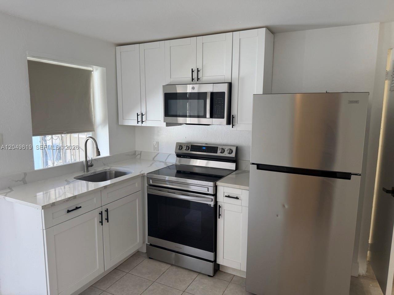 A kitchen features white cabinets, stainless steel appliances, and light-colored countertops with a sink — 219 SW 21st Ave # 5, Miami FL 33135, MIAMI, FL