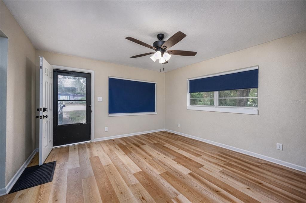 An empty room with light wood-look flooring, a ceiling fan, and two windows with blue shades — 1503 SE 28TH PLACE, GAINESVILLE, FL