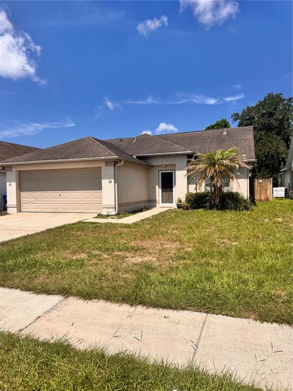 A single-story house with a beige stucco exterior, a two-car garage, and a palm tree — 2070 SARAH LOUISE DRIVE, BRANDON, FL