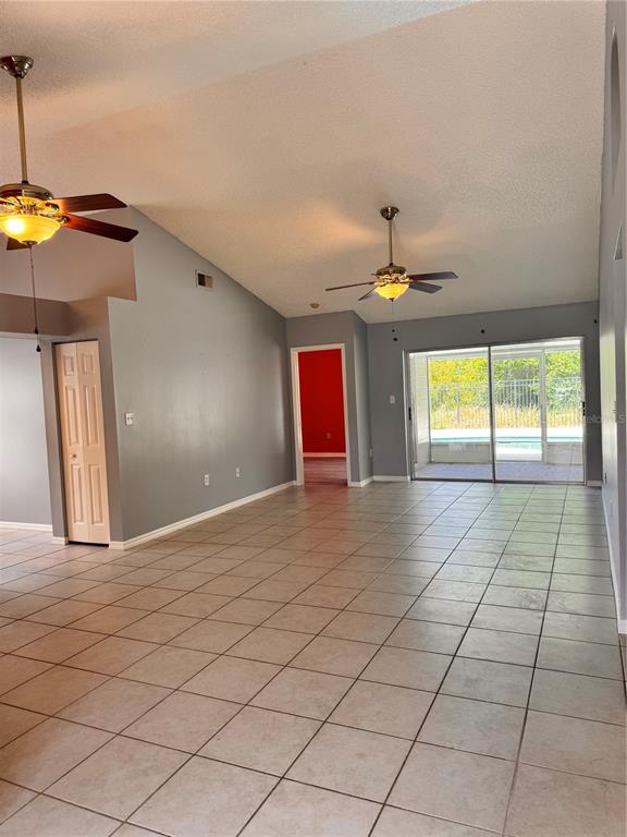 A living room with vaulted ceilings, tile flooring, two ceiling fans, and a sliding glass door — 2070 SARAH LOUISE DRIVE, BRANDON, FL