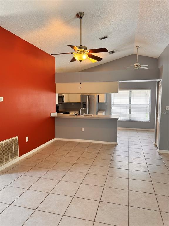 A room with a red wall, tiled floor, vaulted ceiling, and a kitchen breakfast bar — 2070 SARAH LOUISE DRIVE, BRANDON, FL