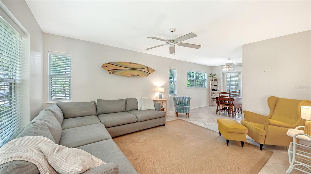 A living room features a grey sectional sofa, a yellow armchair, and a surfboard wall decoration — 2304 63RD STREET COURT W, BRADENTON, FL