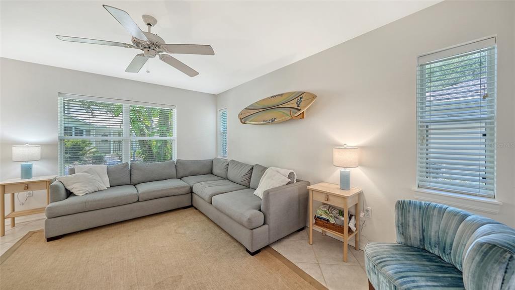 A living room features a gray sectional sofa, a surfboard wall decoration, and two windows — 2304 63RD STREET COURT W, BRADENTON, FL